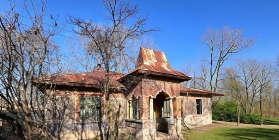Casa Bufnița, with its distinctive red roof and entrance, among trees